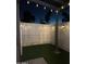 Evening shot of a small backyard featuring fresh artificial grass, privacy fencing, and festive string lights at 286 W Palomino Dr # 78, Chandler, AZ 85225