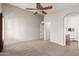 Spacious bedroom features a ceiling fan and neutral carpet, adjacent to an en-suite bathroom at 29151 N Lilly Ln, San Tan Valley, AZ 85143