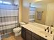 Neutral bath with a shower featuring a gray striped curtain, gray accent rug, white toilet, mirror and vanity at 2934 W Peggy Dr, San Tan Valley, AZ 85144