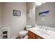 A cozy half bathroom features a vanity with a sink, toilet, decorative wall art and neutral-toned walls at 2934 W Peggy Dr, San Tan Valley, AZ 85144