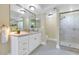 Bright bathroom with granite countertop, white cabinets, large mirror, and walk-in shower at 34 E Boca Raton Rd, Phoenix, AZ 85022