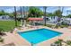 Community pool featuring a red tile shade structure, lounge seating, and meticulous landscaping surrounded by palm trees at 34 E Boca Raton Rd, Phoenix, AZ 85022