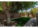 Landscaped backyard with artificial turf, paver patio, and mature tree providing shade at 4318 N 180Th Dr, Goodyear, AZ 85395