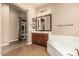 Luxurious bathroom with dual sinks, soaking tub, vanity lighting, tiled floors, and a walk in shower at 4318 N 180Th Dr, Goodyear, AZ 85395