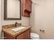 Powder bathroom features a granite countertop, cherry cabinets, bronze fixtures, and framed mirror at 4318 N 180Th Dr, Goodyear, AZ 85395