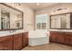 Luxurious bathroom with dual sinks, soaking tub, vanity lighting, tiled floors and windows at 4318 N 180Th Dr, Goodyear, AZ 85395