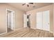 Bedroom with wood-look floors, ceiling fan and access to multiple closets and a bathroom at 4318 N 180Th Dr, Goodyear, AZ 85395