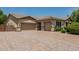 Exterior shot showcasing the three-car garage and extended brick driveway and landscaped front yard at 4318 N 180Th Dr, Goodyear, AZ 85395