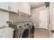 Functional laundry room with a sink, modern washer/dryer, built-in shelves, and tile flooring at 4318 N 180Th Dr, Goodyear, AZ 85395