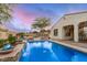 Backyard pool with waterfalls, desert landscaping, hardscape, trees, and partial home view at 4453 S Huachuca Way, Chandler, AZ 85249