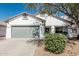 Charming single-story home featuring a gray two-car garage and a well-maintained front yard with mature landscaping at 513 S 115Th Dr, Avondale, AZ 85323