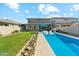 Backyard featuring a modern in-ground pool, stone tile coping, and green lawn at 8754 W San Juan Ave, Glendale, AZ 85305