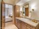 Bathroom featuring double sinks, gold fixtures, wood cabinetry, and a view to the bedroom at 9270 E Thompson Peak Pkwy # 347, Scottsdale, AZ 85255