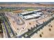 An aerial view shows a well-planned community with a school, baseball field, and neat rows of houses under a clear sky at 9624 E Thunderbolt Ave, Mesa, AZ 85212