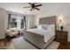 Serene primary bedroom featuring a plush bed, two comfy chairs, and a view of the landscaped backyard at 9904 E South Bend Dr, Scottsdale, AZ 85255