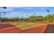 Community tennis court with a red surface, surrounded by trees and lighting at 9904 E South Bend Dr, Scottsdale, AZ 85255