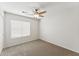 Carpeted bedroom featuring a ceiling fan and natural light from a window, ideal for relaxation and comfort at 1029 E Jasper Dr, Gilbert, AZ 85296