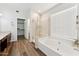 Well-lit bathroom with a large tub, glass-enclosed shower, and wood-look flooring, offering a spa-like experience at 1029 E Jasper Dr, Gilbert, AZ 85296