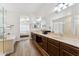 Bright main bathroom showcasing dual sinks, dark wood cabinets, stylish flooring, and an open doorway to the bedroom at 1029 E Jasper Dr, Gilbert, AZ 85296