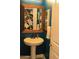 Stylish powder room featuring a pedestal sink, framed mirror, dark teal accent wall, and contemporary design at 1100 S 176Th Ave, Goodyear, AZ 85338