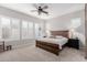 Well-lit bedroom featuring a wooden bed frame, modern fan and plantation shutters on the windows at 14360 W Windrose Dr, Surprise, AZ 85379