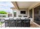 Outdoor kitchen area equipped with bar seating, grill, sink, and tiled backsplash at 14360 W Windrose Dr, Surprise, AZ 85379