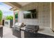 Outdoor kitchen with built-in grill, blackstone and TV for cooking and entertainment in backyard area at 14360 W Windrose Dr, Surprise, AZ 85379