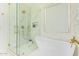 Bright bathroom featuring a stand alone tub, glass shower with gold fixtures, and marble wall and flooring at 16609 N 40Th Dr, Phoenix, AZ 85053