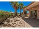 Desert backyard featuring a covered patio, decorative water feature, and mature palm trees at 16704 W Oracle Rim Dr, Surprise, AZ 85387
