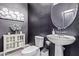 Stylish powder room featuring dark walls, patterned tile flooring, pedestal sink, and decorative wall art at 1914 N Marketside Ave, Buckeye, AZ 85396