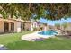 Lush backyard features a serene pool, rock waterfall, green lawn, desert landscaping, and a tranquil ambiance at 20507 W Daniel Pl, Buckeye, AZ 85396