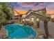 Inviting backyard features a sparkling pool, desert landscaping, and patio area under a beautiful sky at sunset at 20507 W Daniel Pl, Buckeye, AZ 85396