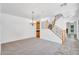 Spacious dining area featuring a modern chandelier, neutral carpet, wood-trimmed staircase, and bright natural light at 20507 W Daniel Pl, Buckeye, AZ 85396