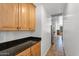 Hallway leading to the kitchen featuring wood cabinets with black countertop at 20507 W Daniel Pl, Buckeye, AZ 85396