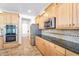 Kitchen featuring wood cabinets, stainless steel appliances, tile backsplash and black countertops at 20507 W Daniel Pl, Buckeye, AZ 85396