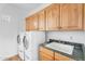 Laundry room with white washer and dryer, wood cabinets, and sink at 20507 W Daniel Pl, Buckeye, AZ 85396