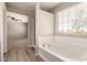 A white soaking tub under a window, leading to a bedroom with a ceiling fan at 21039 E Avenida Del Valle --, Queen Creek, AZ 85142
