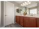 A bathroom vanity with double sinks, wood cabinets, a large mirror, and a white door at 21039 E Avenida Del Valle --, Queen Creek, AZ 85142