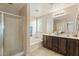 Bright bathroom featuring a glass enclosed shower, soaking tub and a double sink vanity with dark wood cabinets at 23787 W Yavapai St, Buckeye, AZ 85326