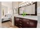 Bathroom featuring dual sinks, dark wood cabinets, marble counters, and open access to the bedroom at 3055 N Red Mtn # 77, Mesa, AZ 85207