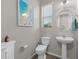 Well-lit bathroom featuring a pedestal sink, toilet, decorative mirror, and stylish fixtures at 3865 E Dogwood Pl, Chandler, AZ 85286