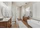 Elegant bathroom with dual vanities, a modern soaking tub, and a unique glass block wall detail at 42429 N Cross Timbers Ct, Anthem, AZ 85086