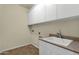 Functional laundry room with a utility sink, white cabinets, and tile floors at 5223 W Bent Tree Dr, Phoenix, AZ 85083