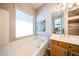 A luxurious tub is set beneath a bright window in this well-lit en-suite bathroom at 5416 W Village Dr, Glendale, AZ 85308