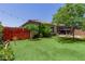 This home's backyard features lush grass, a red fence, patio, and mature landscaping at 5659 N 195Th Dr, Litchfield Park, AZ 85340