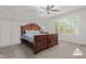 Bedroom with a large wood-framed bed, soft carpet, and windows offering a view of the surrounding greenery at 5659 N 195Th Dr, Litchfield Park, AZ 85340