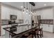 Modern kitchen with stainless steel appliances, white cabinetry, and a large island with a black countertop at 5659 N 195Th Dr, Litchfield Park, AZ 85340
