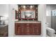 Bathroom featuring a double sink vanity with granite countertop, decorative mirror and tile backsplash at 6715 S Lakeshore Dr, Tempe, AZ 85283