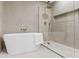 Contemporary bathroom featuring a soaking tub, a rainfall shower, and sleek marble tiling at 7409 E Pleasant Run, Scottsdale, AZ 85258