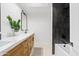 Stylish bathroom featuring a double sink vanity with wood cabinets and a shower with sleek, dark vertical tiles at 7409 E Pleasant Run, Scottsdale, AZ 85258